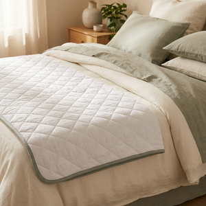 BESIDE waterproof bed layer on a made bed, three-quarter angle